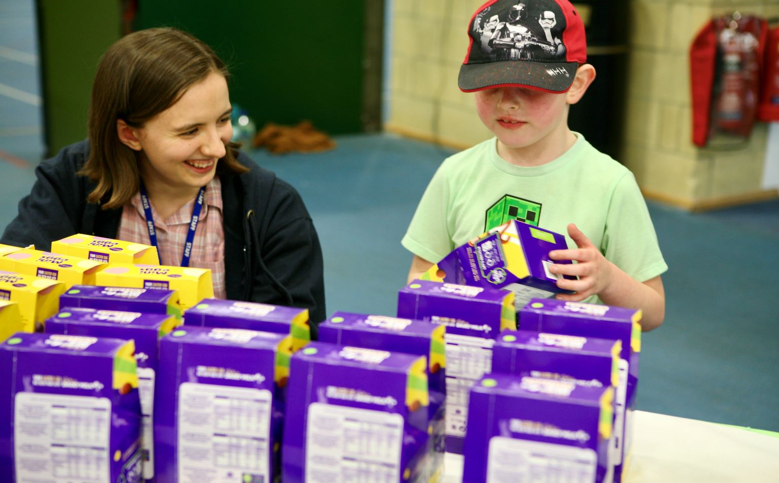 Alex from Families InFocus with a young boy, looking at a table of Easter eggs. The boy is wearing a cap.