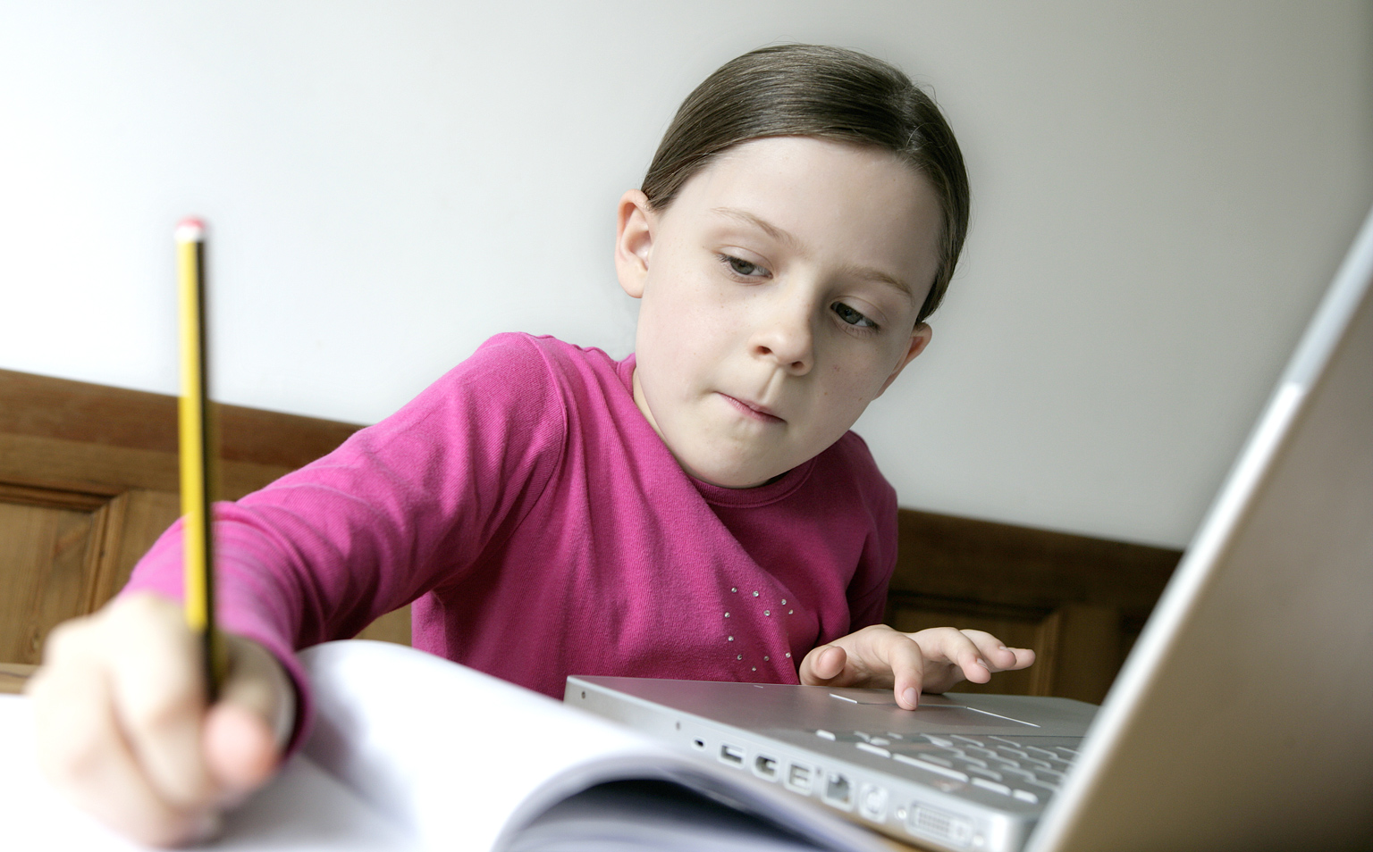 Girl in a pink t shirt sat working at a laptop